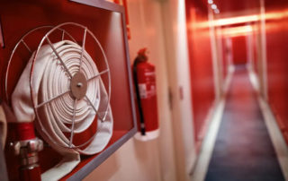 Carrete de una manguera contra incendios de una BIES o boca de incendio con un extintor visible en un hotel
