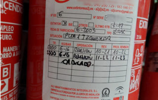 Extintor con etiqueta de mantenimiento que muestra detalles de revisiones, caducidad y especificaciones técnicas perteneciente a extintores A2J