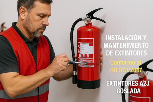 Técnico de mantenimiento con chaleco de seguridad rojo instalando extintores rojos de incendios. La imagen enfoca claramente sus manos mientras instala el extintor. Al fondo, otros extintores desenfocados sugieren un entorno profesional.