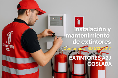 Técnico de mantenimiento con chaleco de seguridad rojo con el logotipo de extintores a2J haciendo el mantenimiento de equipos contra incendios. La imagen enfoca claramente sus manos mientras inspecciona los equipos. Al fondo, otros equipos desenfocados de sistemas contra incendios que sugieren un entorno profesional.